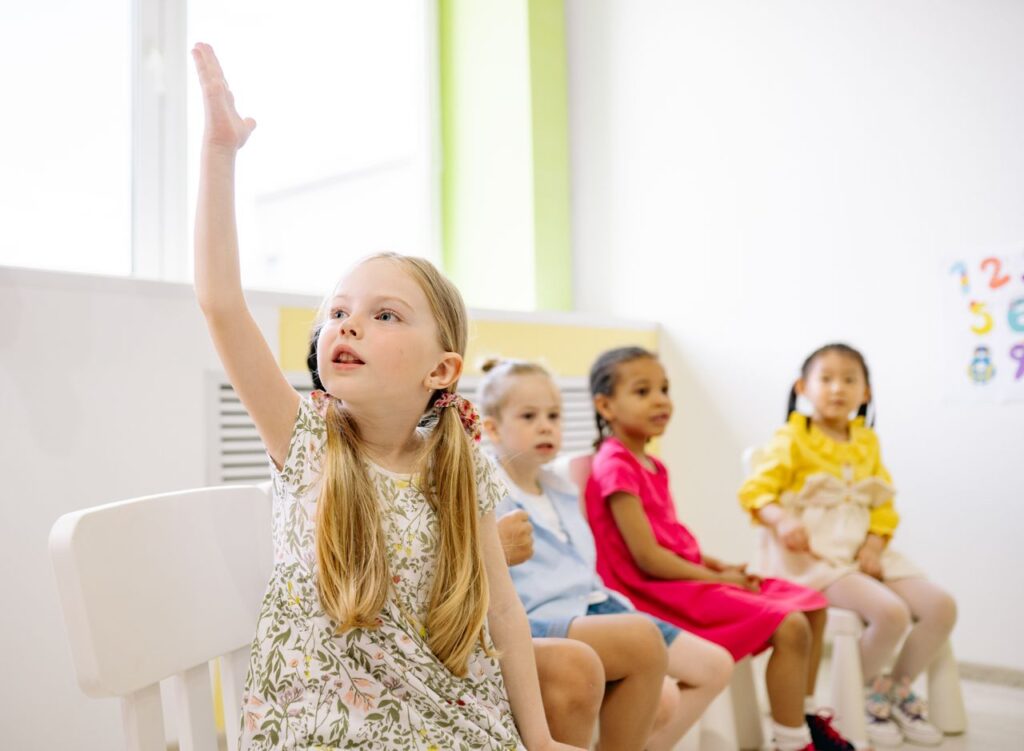 Mastering the First Impression: Your intriguing post title goes here Kindergarten students in a classroom raising hands to participate in learning activities.